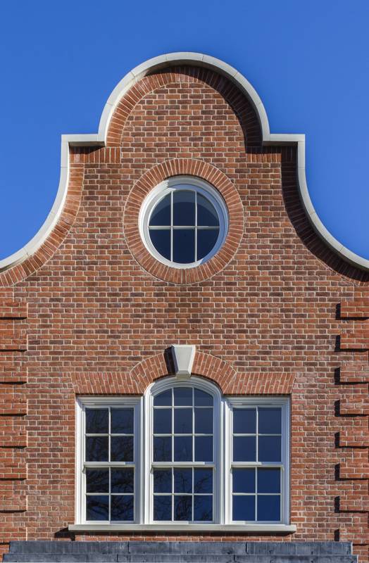 Bespoke timber windows - A detailed brick facade with a decorative arched top, featuring a circular window above three rectangular windows.