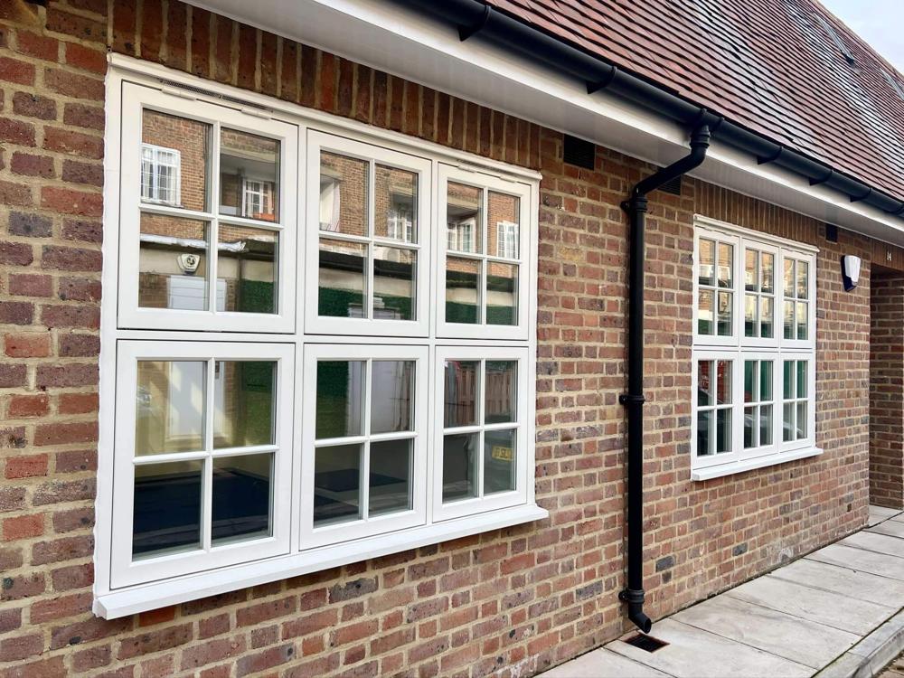 Two bespoke white timber flush casement windows in a new brick house.
