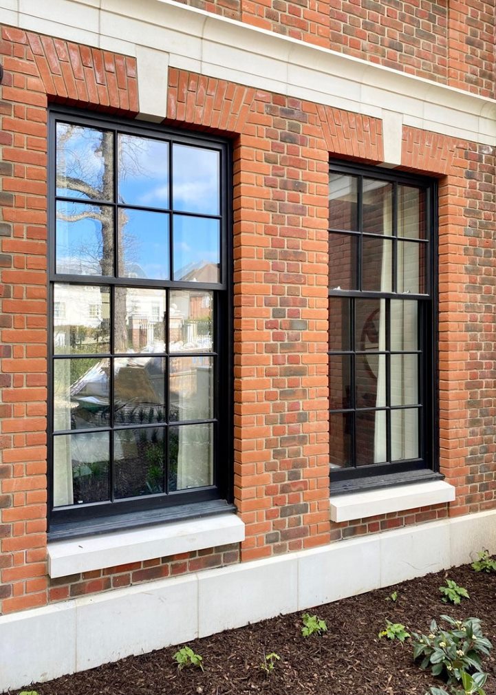 pair of black timber sash windows installed within red brick building