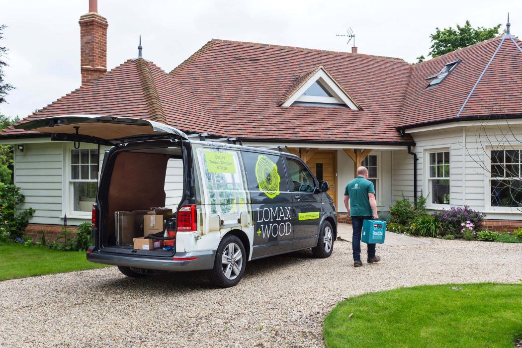 Lomax + wood van outside bespoke home with worker carrying tools
