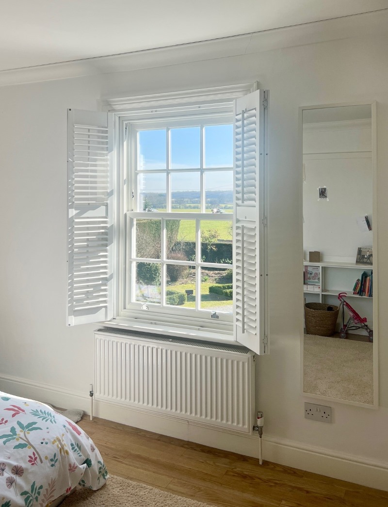 white sliding sash window in bedroom with view looking out on to garden and green fields