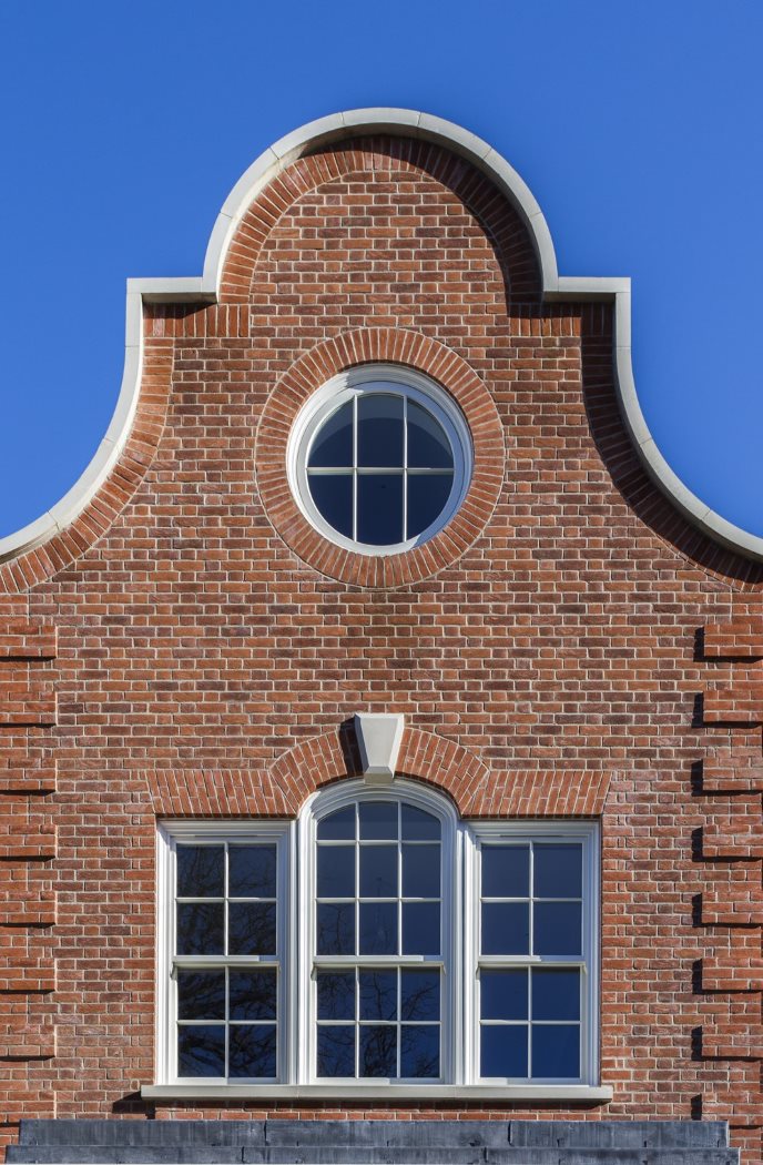 Bespoke timber windows - A detailed brick facade with a decorative arched top, featuring a circular window above three rectangular windows.
